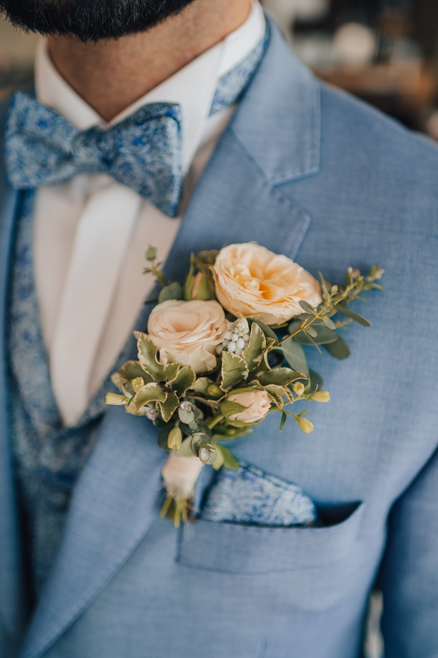 Modrý oblek s květinovou korsáží do klopy.