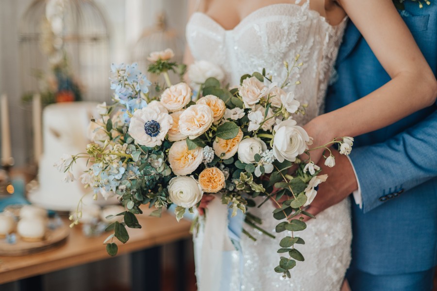Svatební kytice v broskvové a světle modré barvě.